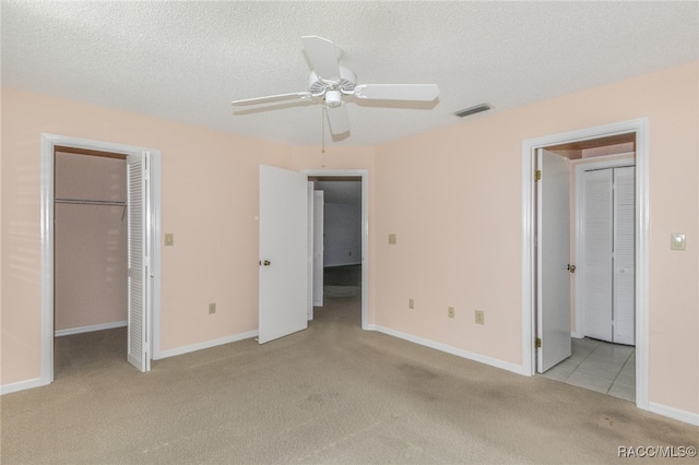 unfurnished bedroom featuring a textured ceiling, light colored carpet, a spacious closet, and ceiling fan