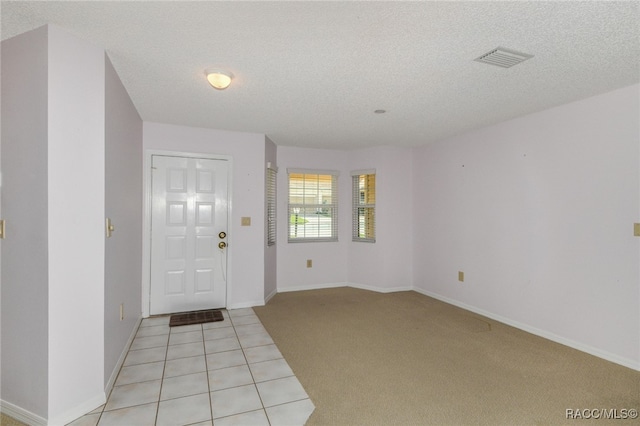 foyer entrance featuring light colored carpet and a textured ceiling