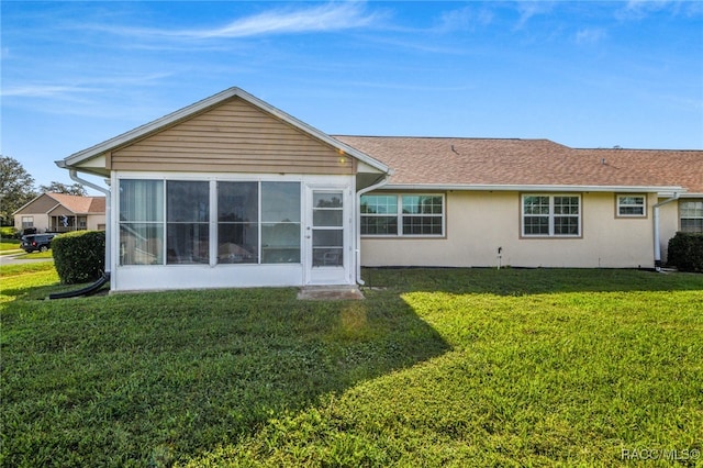 rear view of house with a sunroom and a yard