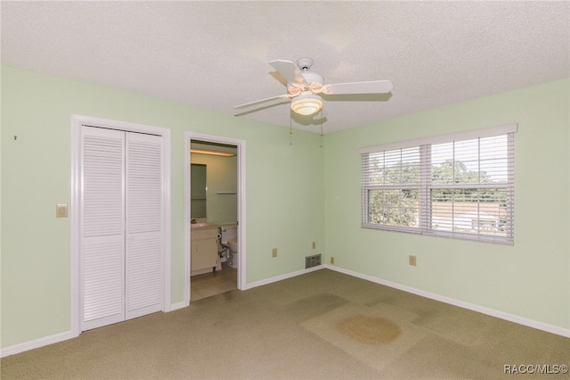 unfurnished bedroom with carpet flooring, ceiling fan, a textured ceiling, and a closet