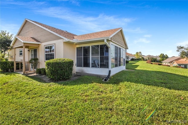 back of house with a lawn and a sunroom