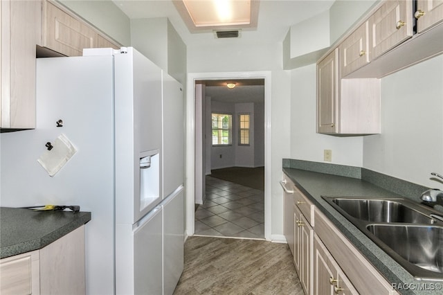 kitchen featuring light brown cabinets, hardwood / wood-style floors, white fridge with ice dispenser, and sink