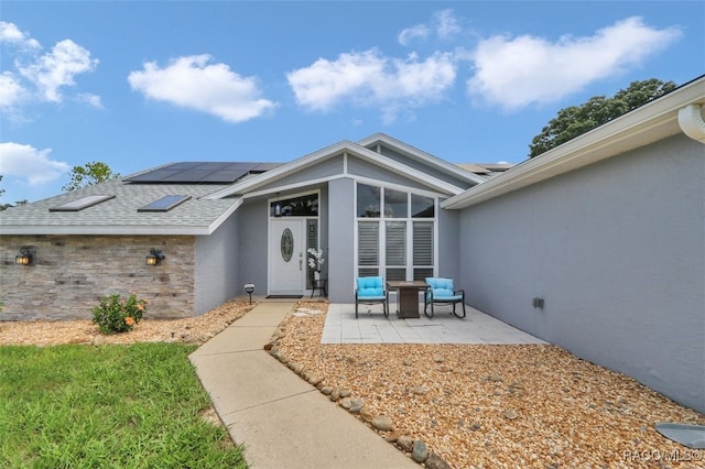 391 E Falconry Ct, Hernando, FL 34442 - entrance to property featuring solar panels, stucco siding, a patio area, and a shingled roof