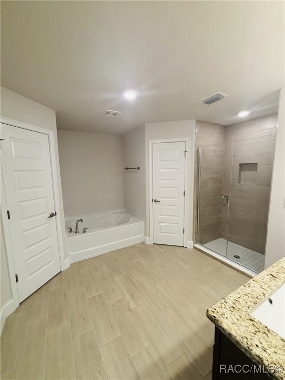 bathroom featuring vanity, plus walk in shower, and hardwood / wood-style floors