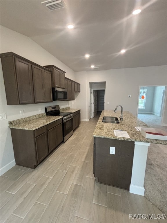 kitchen featuring light stone countertops, sink, stainless steel range with electric cooktop, and dark brown cabinets