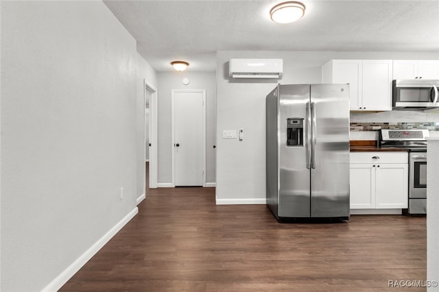 kitchen with appliances with stainless steel finishes, dark hardwood / wood-style floors, white cabinetry, and an AC wall unit