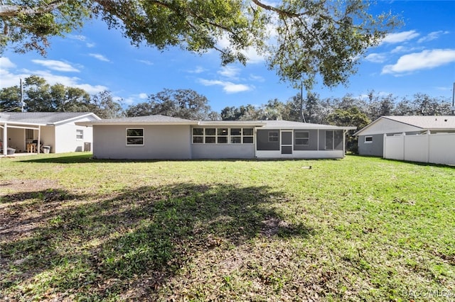 rear view of property with a sunroom and a lawn