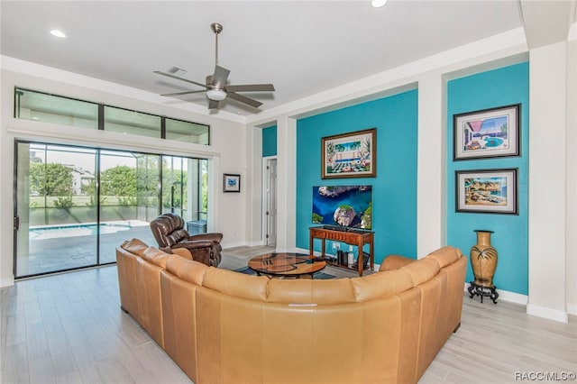 living room featuring ceiling fan, light wood-type flooring, and crown molding