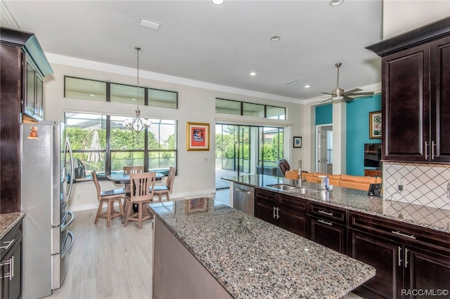 kitchen featuring backsplash, ornamental molding, stainless steel appliances, sink, and hanging light fixtures