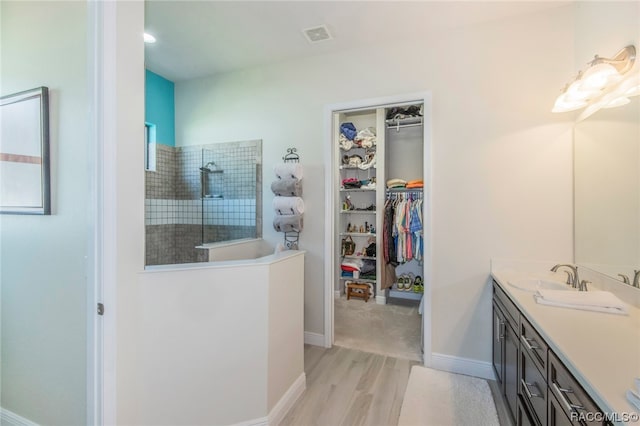 bathroom featuring a tile shower, vanity, and hardwood / wood-style flooring