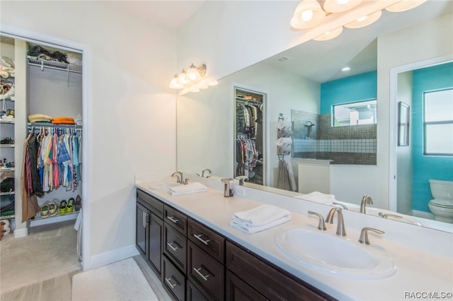 bathroom featuring toilet, vanity, and tiled shower