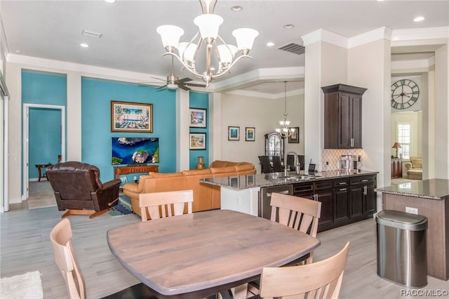 dining area with ceiling fan with notable chandelier, ornamental molding, sink, and light hardwood / wood-style flooring