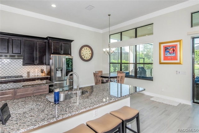 kitchen with light stone countertops, backsplash, stainless steel appliances, sink, and hanging light fixtures