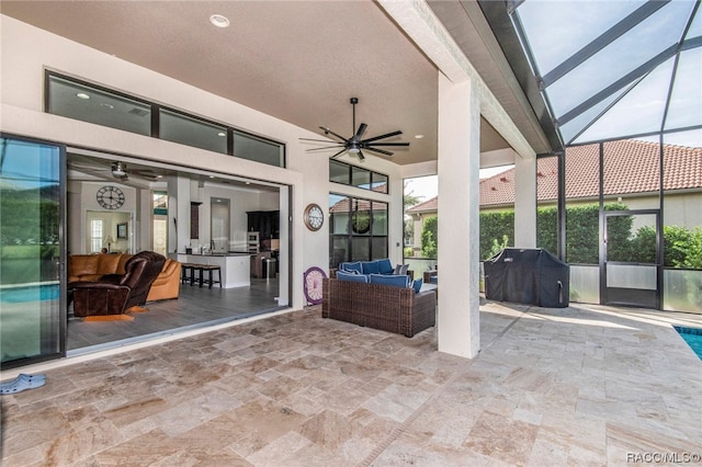 view of patio / terrace featuring glass enclosure, ceiling fan, area for grilling, and an outdoor living space