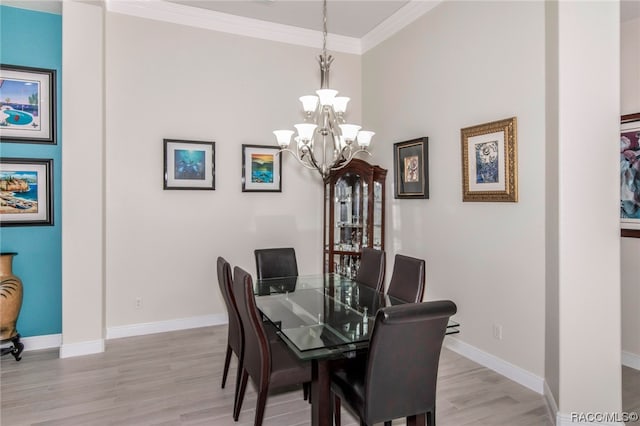 dining area with a notable chandelier, light hardwood / wood-style floors, and crown molding