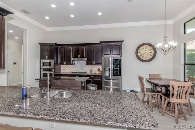 kitchen featuring ornamental molding, dark brown cabinetry, stainless steel appliances, sink, and decorative light fixtures