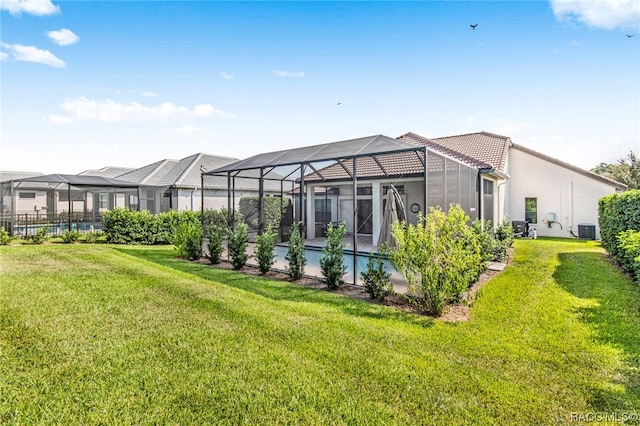 back of property with a lawn, a lanai, and central air condition unit