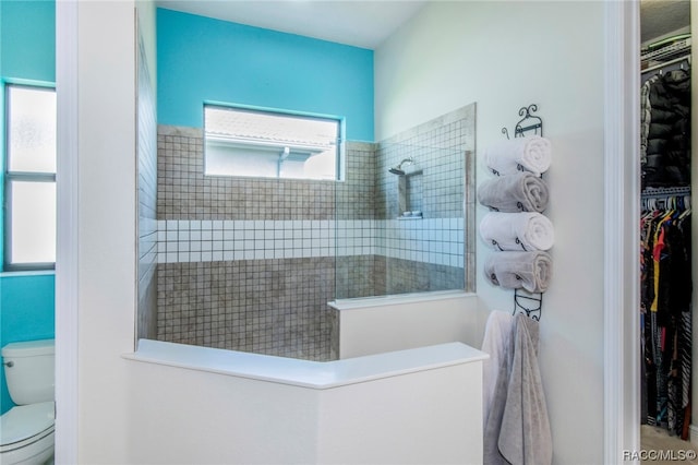 bathroom featuring a tile shower and toilet