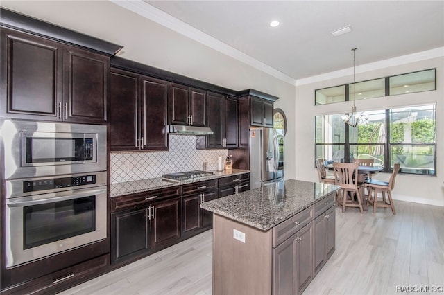 kitchen with appliances with stainless steel finishes, light wood-type flooring, dark stone counters, dark brown cabinetry, and a chandelier