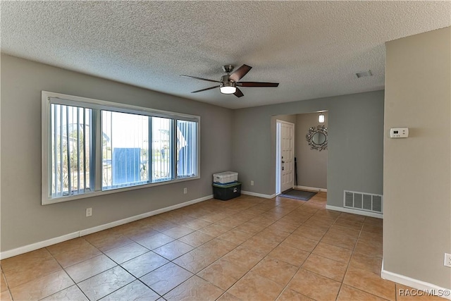 empty room featuring light tile patterned floors, visible vents, baseboards, and a ceiling fan