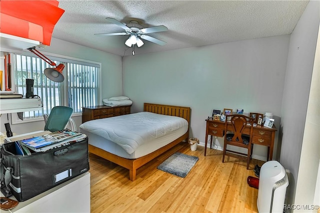 bedroom with a textured ceiling, light wood-style flooring, and a ceiling fan