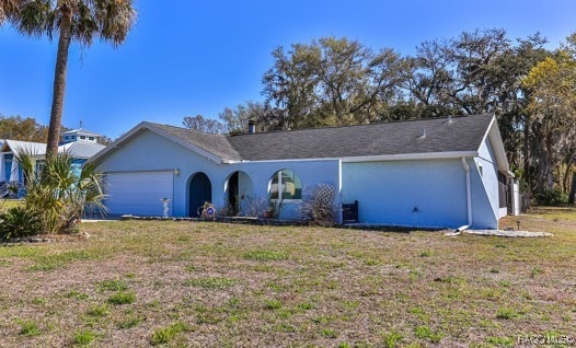 ranch-style house with stucco siding, a front yard, and a garage