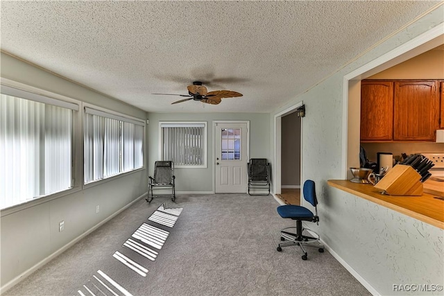 sitting room featuring a textured ceiling, light colored carpet, baseboards, and ceiling fan