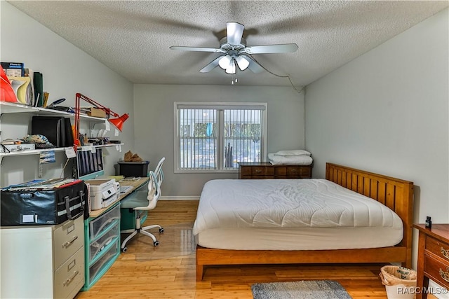 bedroom featuring baseboards, light wood-style flooring, a textured ceiling, and a ceiling fan