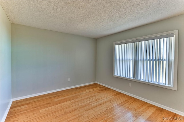 unfurnished room with wood finished floors, baseboards, and a textured ceiling