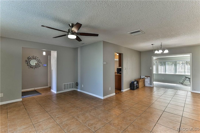 empty room featuring light tile patterned flooring, ceiling fan with notable chandelier, and visible vents