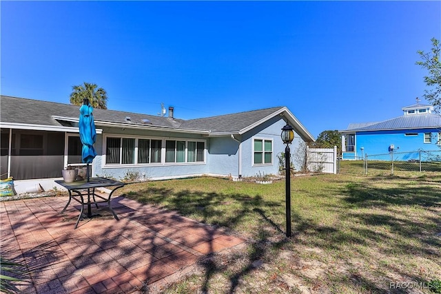 rear view of property featuring stucco siding, a patio, a yard, and fence