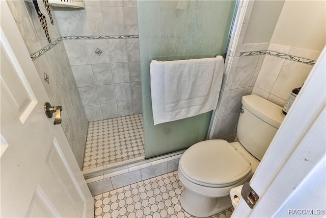 bathroom featuring tile patterned floors, toilet, tile walls, and a stall shower