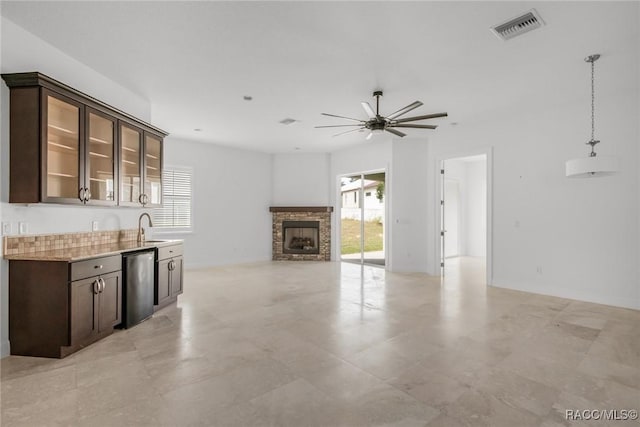 kitchen with dark brown cabinetry, a fireplace, sink, hanging light fixtures, and ceiling fan