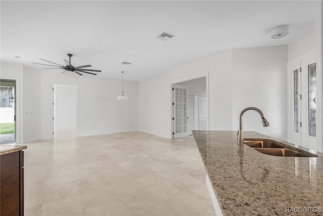 kitchen with light stone countertops, pendant lighting, french doors, sink, and ceiling fan