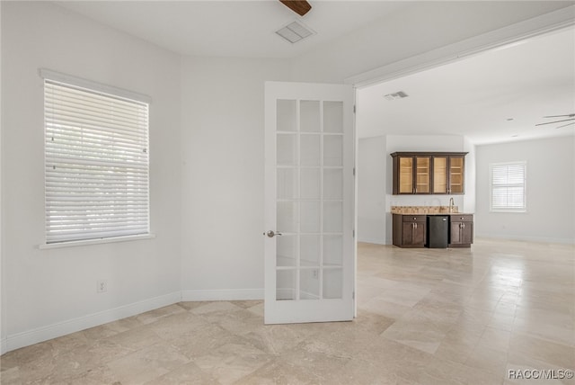 empty room with ceiling fan, indoor bar, and french doors