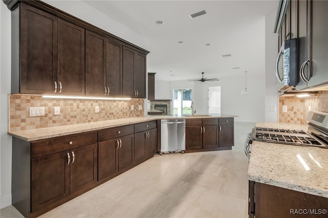 kitchen featuring kitchen peninsula, stainless steel appliances, light stone counters, decorative backsplash, and dark brown cabinetry