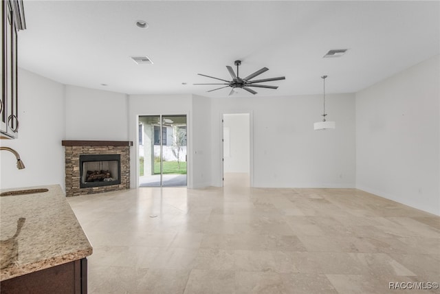 living room with sink, ceiling fan, and a stone fireplace