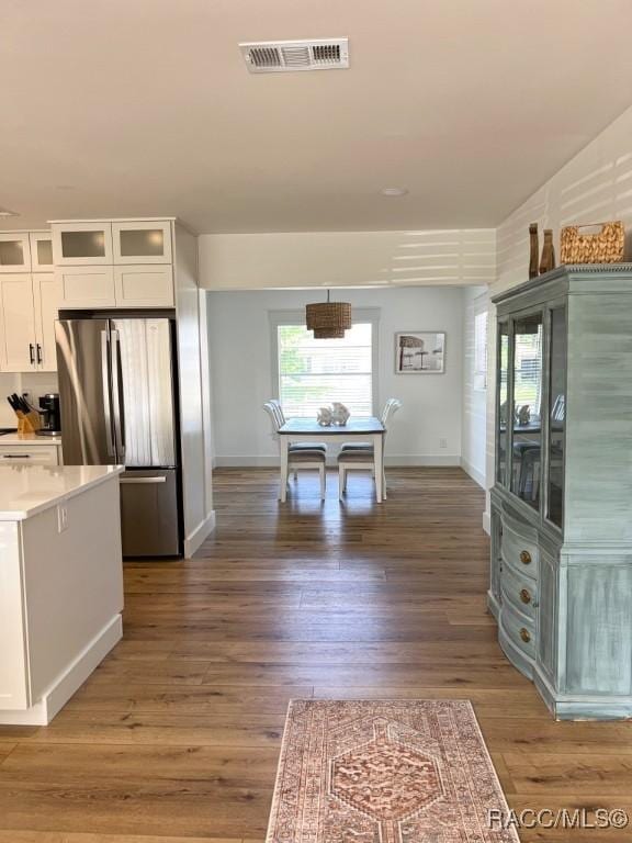 kitchen featuring dark hardwood / wood-style floors, stainless steel fridge, light stone counters, and white cabinets