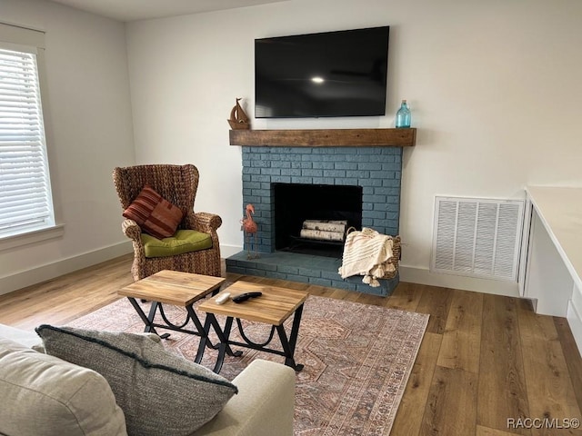 sitting room with a brick fireplace and hardwood / wood-style flooring