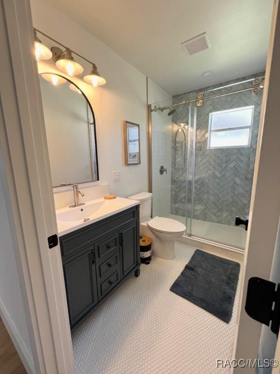 bathroom featuring vanity, toilet, and a shower with shower door