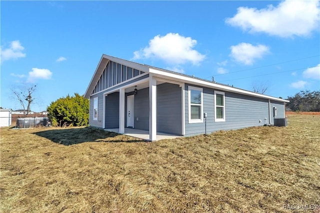 view of side of home featuring a patio, cooling unit, and a lawn