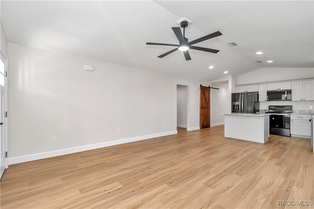 kitchen with stainless steel appliances, white cabinets, a kitchen island, a barn door, and light wood-type flooring