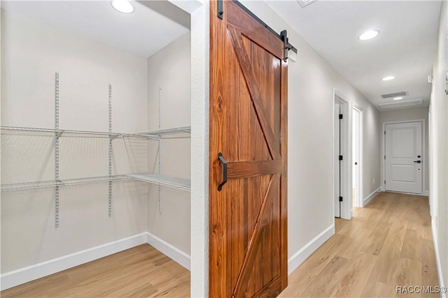 hall with a barn door and light wood-type flooring