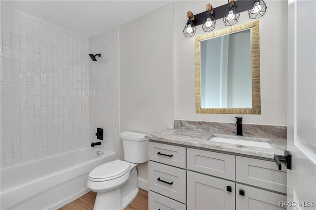 full bathroom with tiled shower / bath combo, vanity, hardwood / wood-style flooring, and toilet