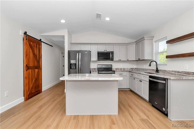 kitchen featuring sink, black appliances, a kitchen island, vaulted ceiling, and a barn door