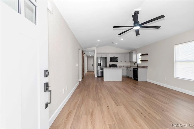 kitchen with lofted ceiling, a center island, light hardwood / wood-style flooring, ceiling fan, and black appliances