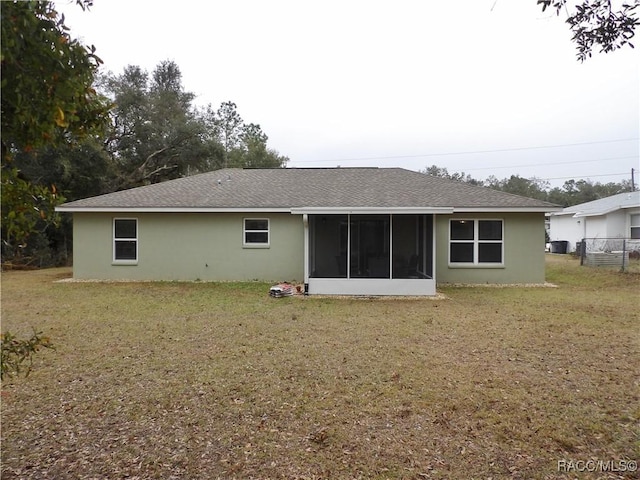 rear view of property with a sunroom and a lawn