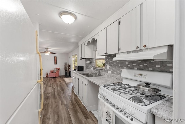 kitchen with under cabinet range hood, white appliances, a sink, light countertops, and backsplash