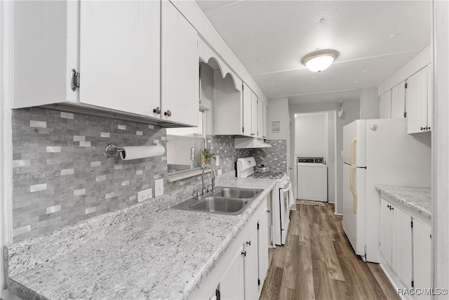 kitchen with white appliances, white cabinets, washer / clothes dryer, light countertops, and a sink