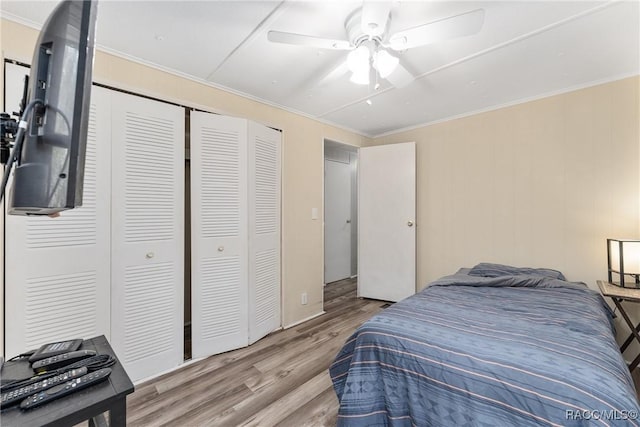 bedroom with a ceiling fan, a closet, ornamental molding, and wood finished floors